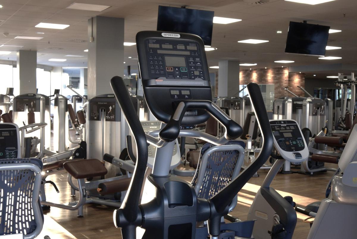 Crosstrainer in Nahaufnahme im Cardiobereich des F4U Wiesbaden, im Hintergrund Kraftgeräte und Monitore an der Decke