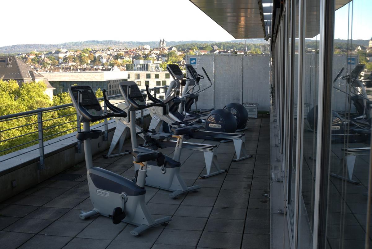 Cardio-Geräte auf der Panoramaterrasse des F4U Wiesbaden mit Blick über die Dächer der Stadt